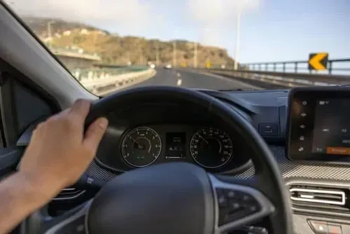 Hand am Lenkrad, Blick durch die Windschutzscheibe auf eine Straße auf Madeira